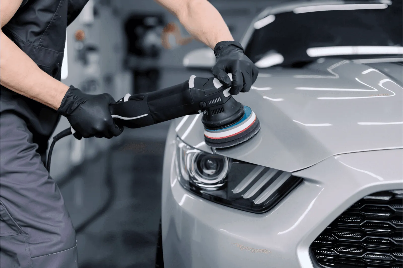 Machine polishing the front of a silver car