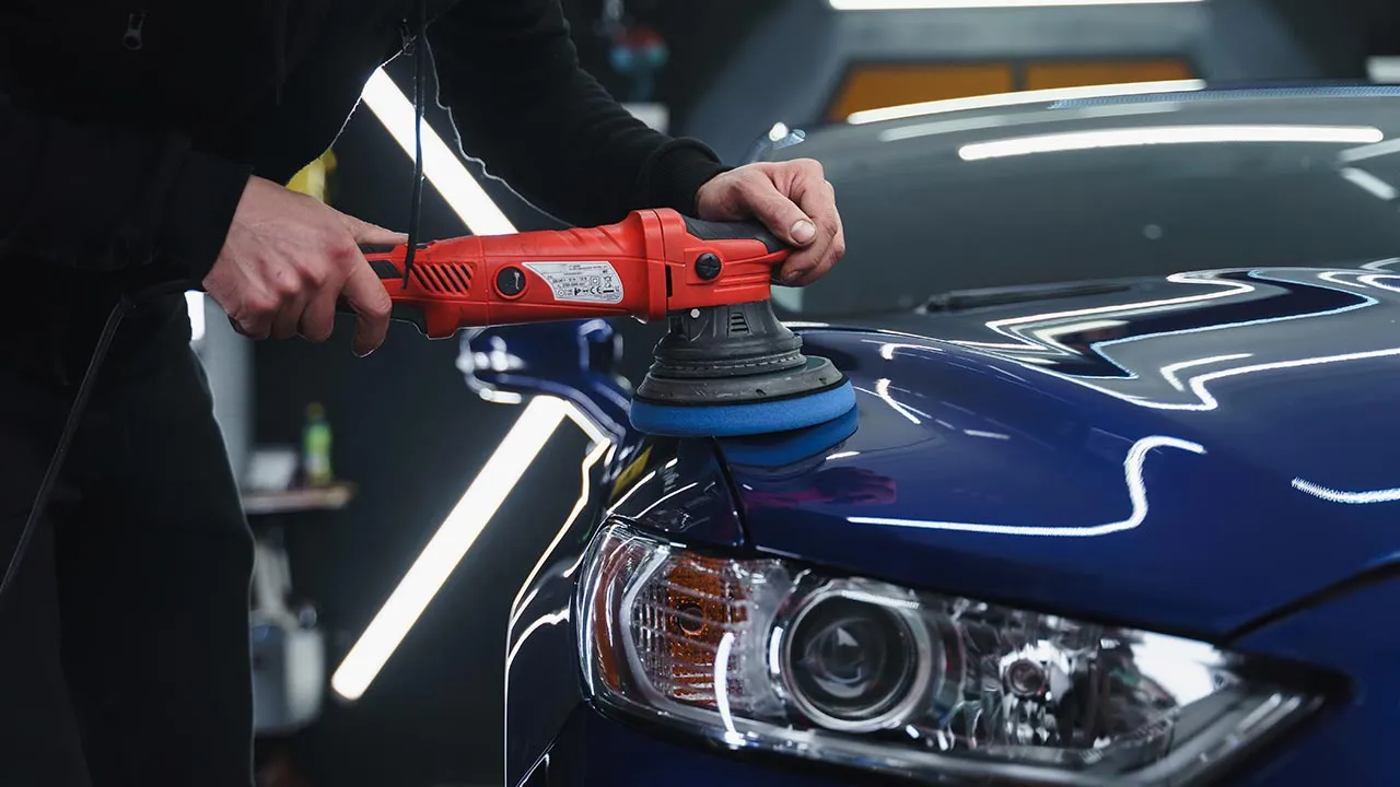 Polisher bringing up deep gloss on a dark blue hood